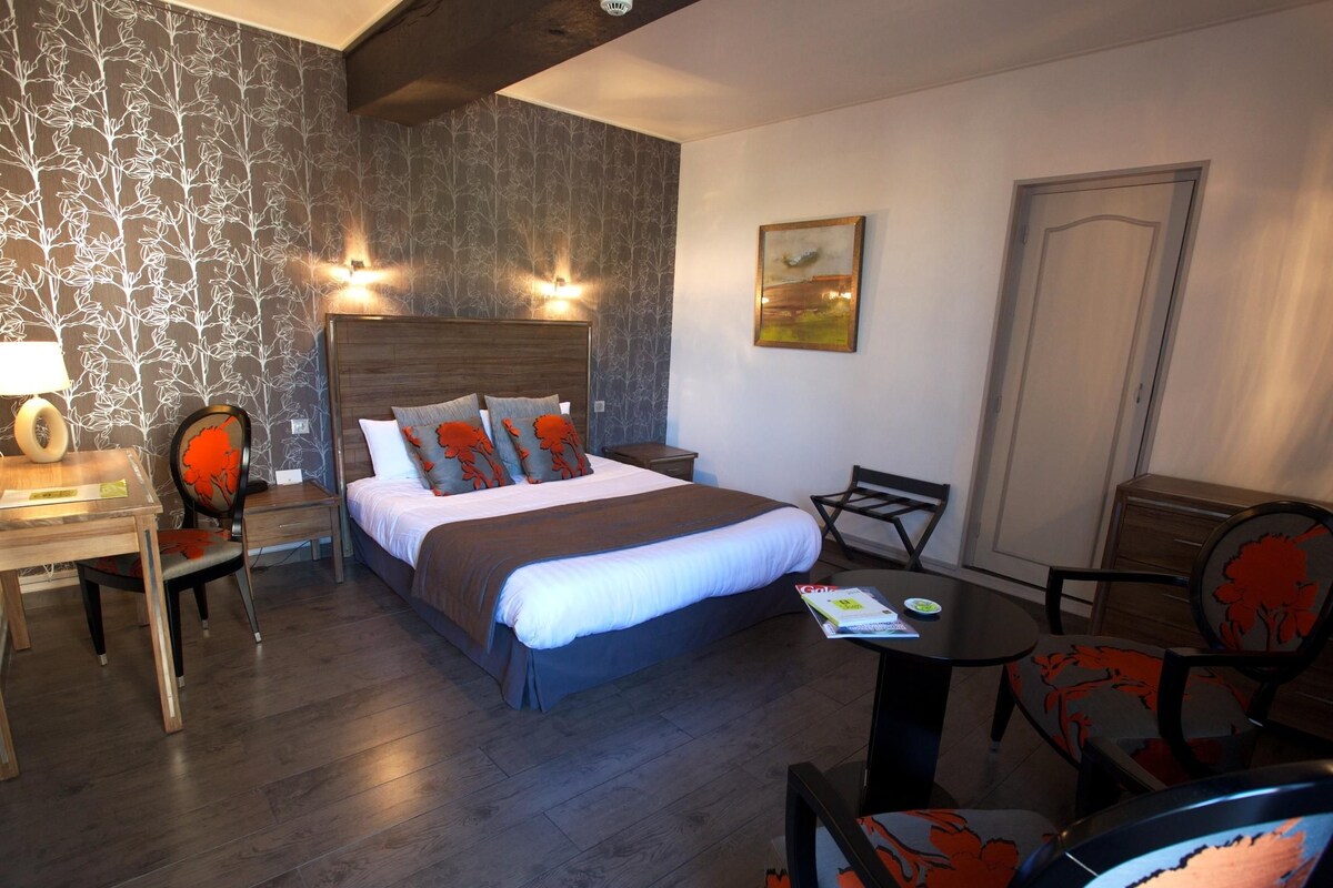Habitación de hotel con cama, escritorio, sillas y una mesa de comedor.