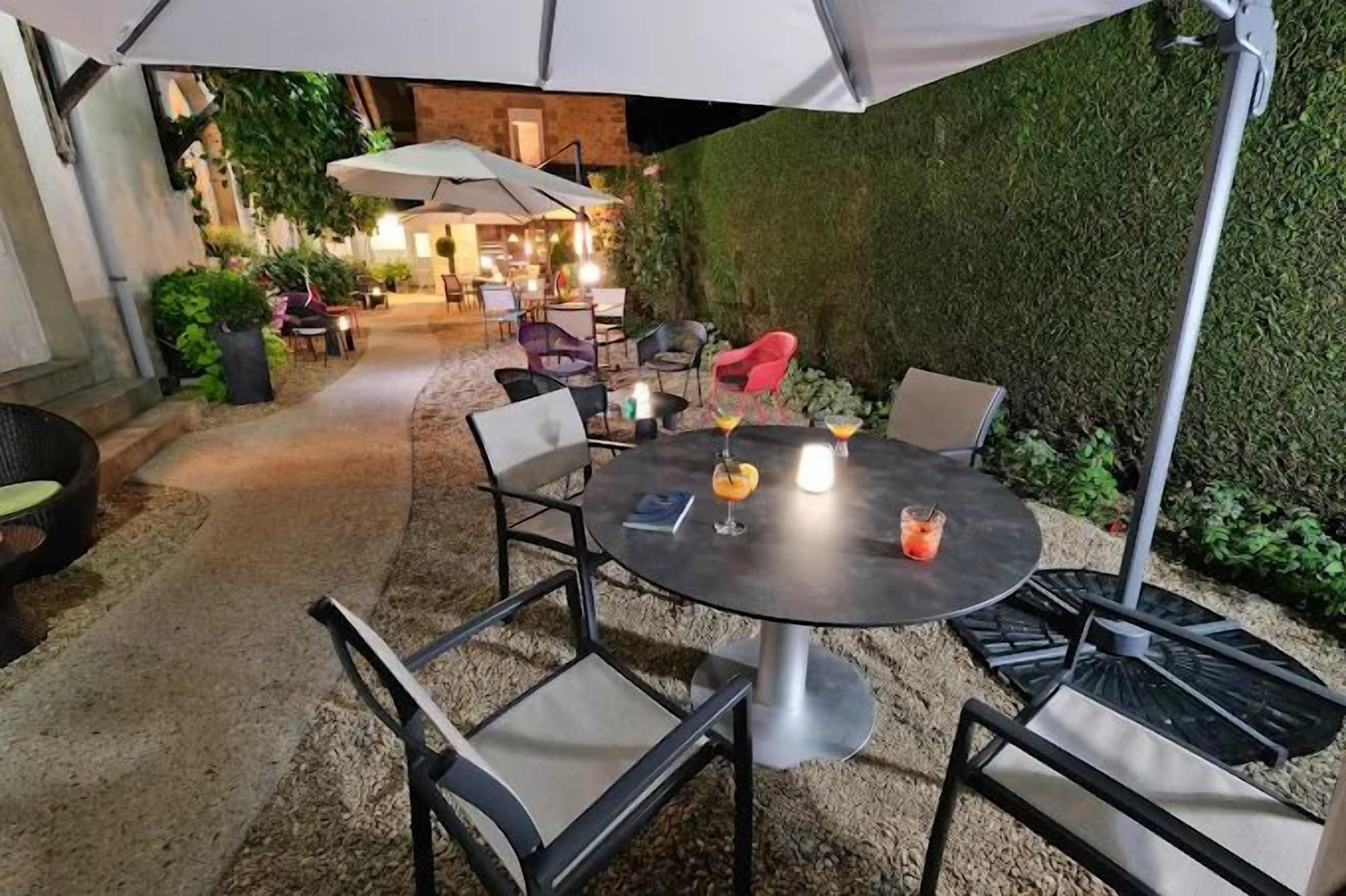An outdoor patio area with a round table, chairs, and umbrellas.