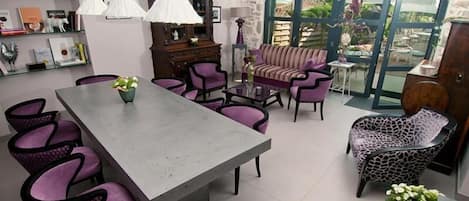 A dining area with a large table, purple chairs, and a patterned armchair.