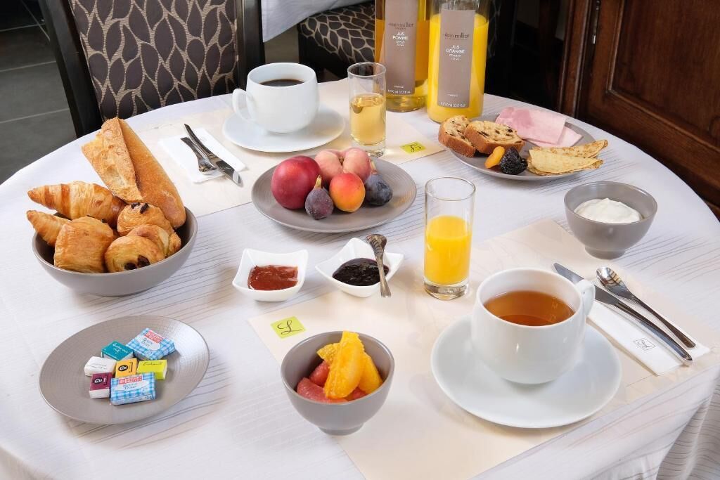 A breakfast table with croissants, fruit, juice, coffee, and condiments.