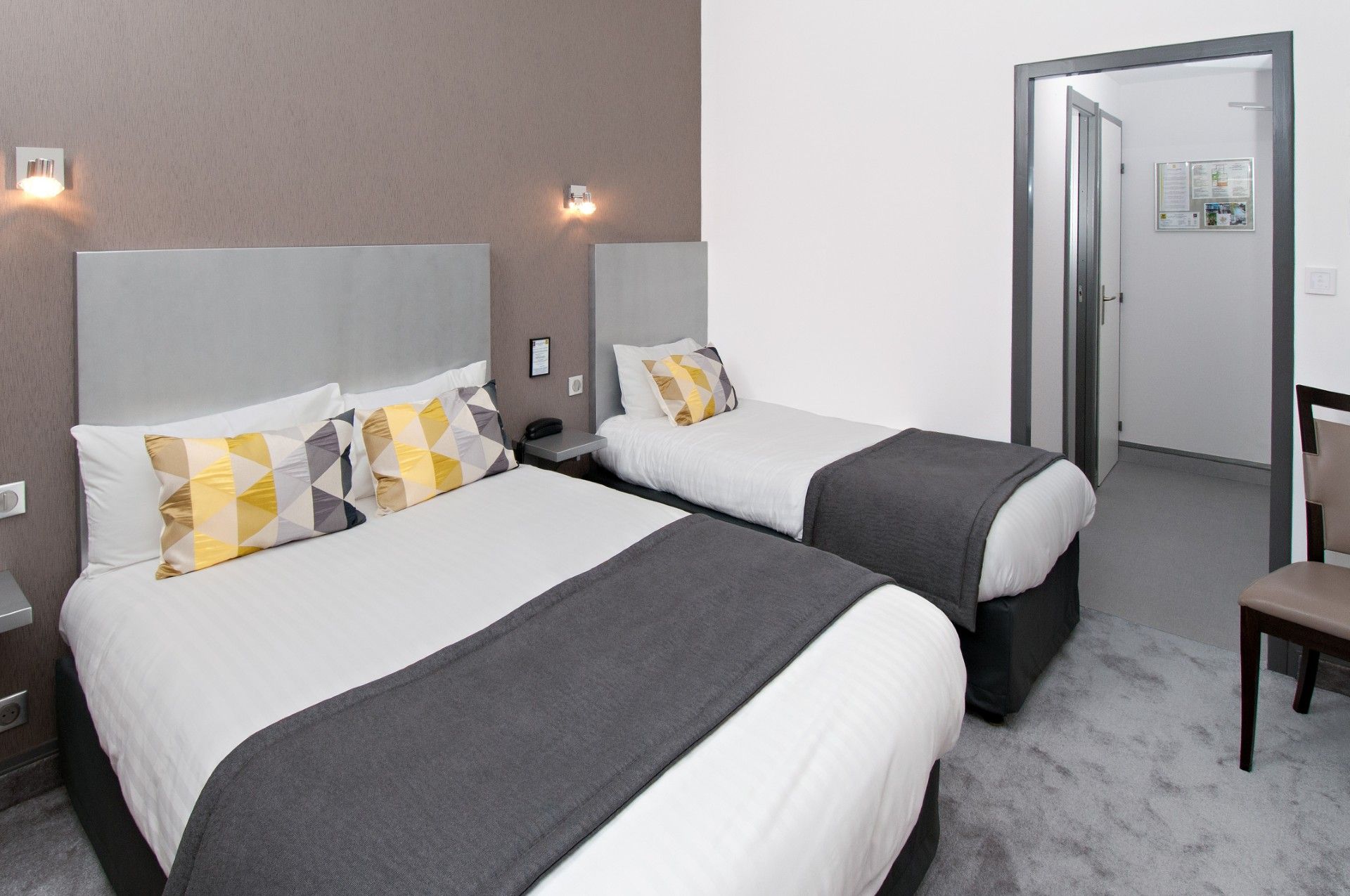 Une chambre d’hôtel avec deux lits, un bureau et une chaise.