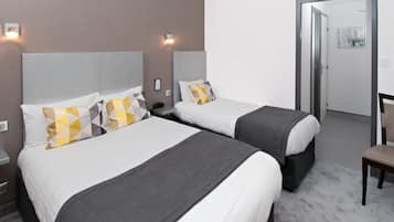 Une chambre d’hôtel avec deux lits, un bureau et une chaise.