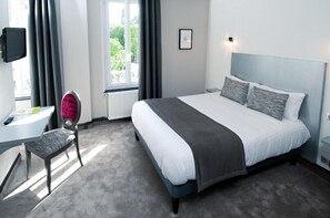 A hotel room with a bed, a desk, a chair, a TV, and a window with curtains. - Hôtel Nougier (Fursac)