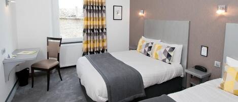 A hotel room with two beds, a desk, a chair, and a window with curtains.
