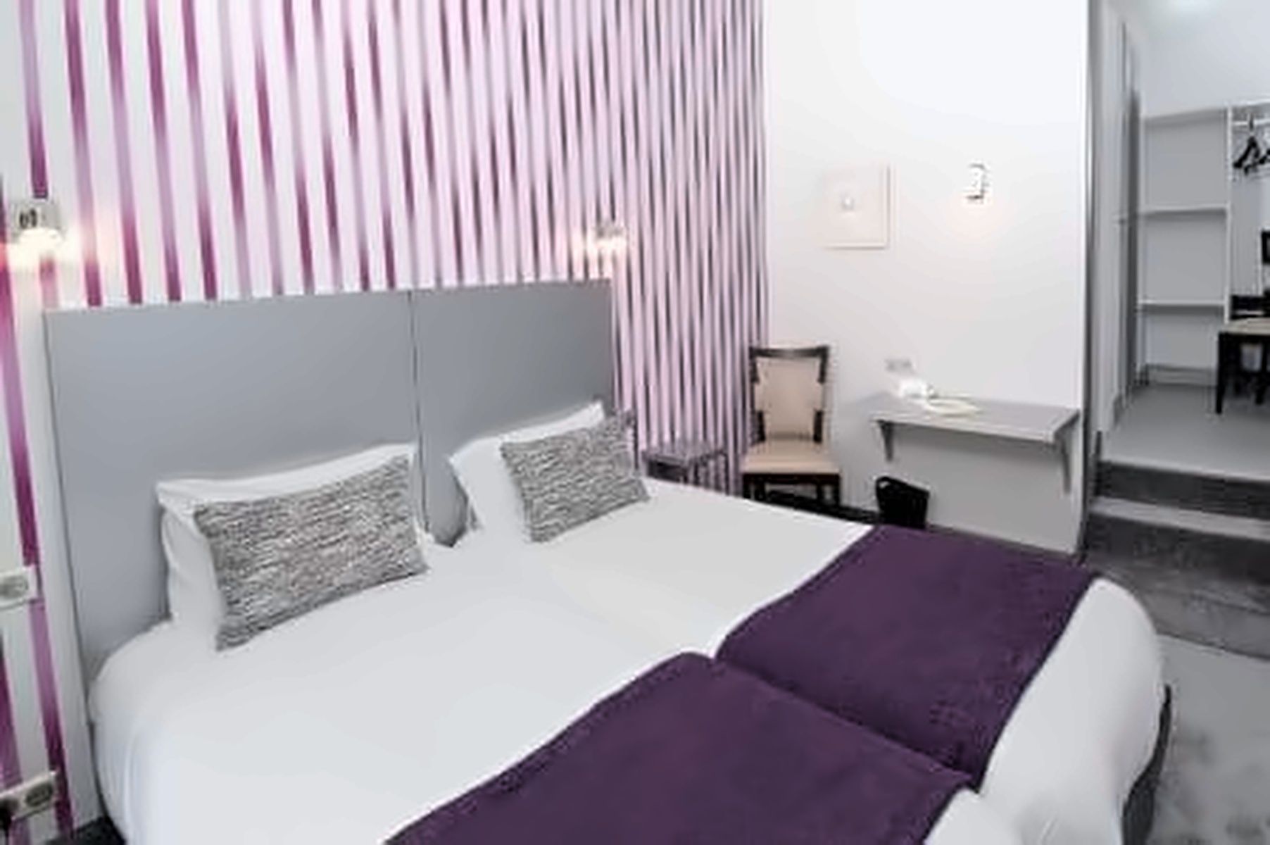 A hotel room with a bed, a desk, and a chair.
