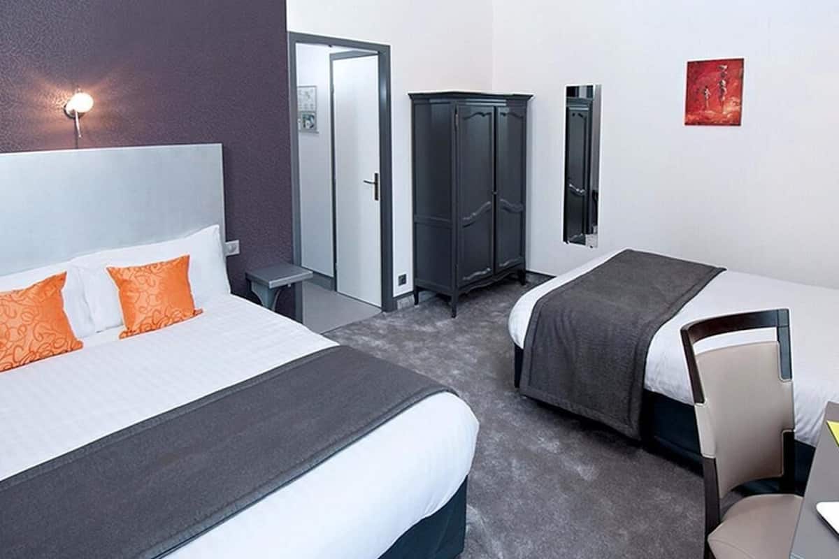 A hotel room with two beds, a wardrobe, a desk, and a chair.