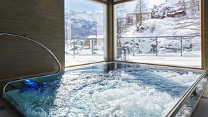 A hot tub with a view of snowy mountains and buildings.