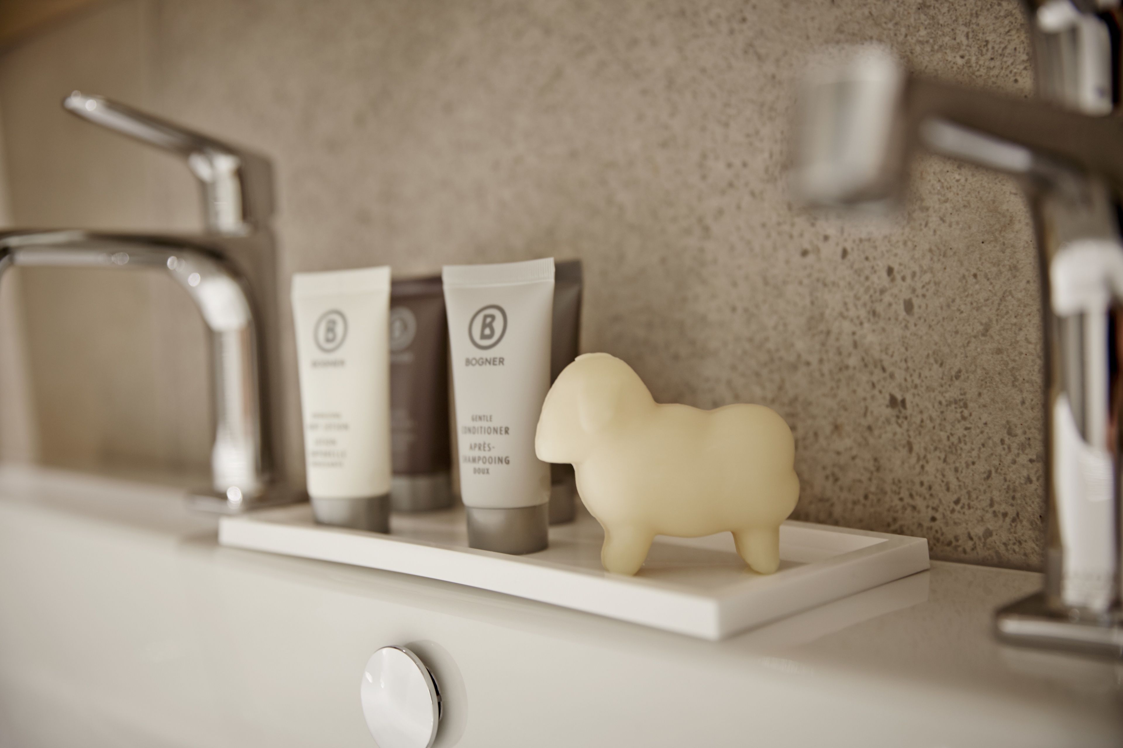 A bathroom shelf with a Booger conditioner, a shampoo, and a soap bar.