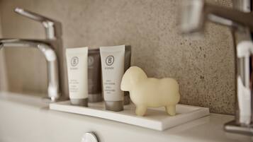 A bathroom shelf with a Booger conditioner, a shampoo, and a soap bar.
