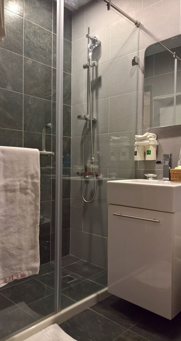A modern bathroom with a glass-enclosed shower, a white vanity, and a towel rack.
