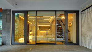 Una entrada moderna a un edificio con puertas de vidrio, una escalera y un interior bien iluminado.