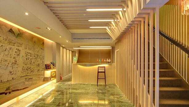 Un moderno vestíbulo de hotel con piso de mármol, una recepción y una escalera.