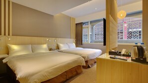 Habitación de hotel con dos camas, un escritorio con hervidor y ventana con vista a un edificio.