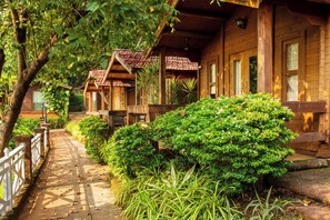 Une cabane en bois avec un toit en tuiles, une véranda et un chemin bordé de verdure.