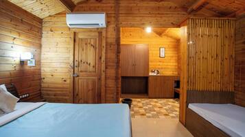 Quarto de cabana de madeira com duas camas, um espaço de cozinha compacto e um ar condicionado.