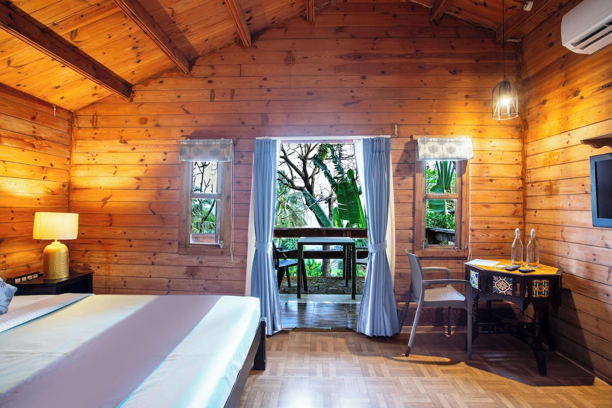 Une pièce de cabane en bois comprenant un lit, une table avec des bouteilles et une chaise.
