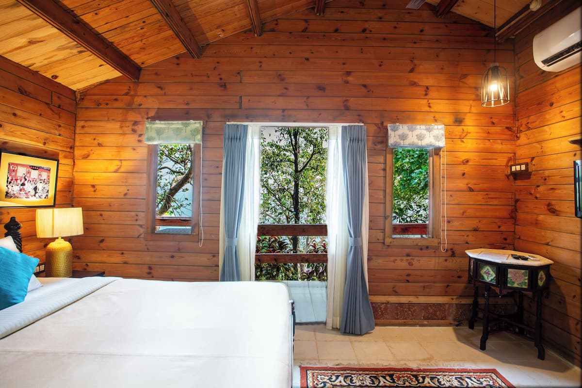 Une chambre dans une cabane en bois, avec un lit, une table et une fenêtre avec des rideaux.