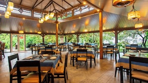 Un espace de restauration intérieur avec des tables et des chaises, de grandes fenêtres et des luminaires suspendus.