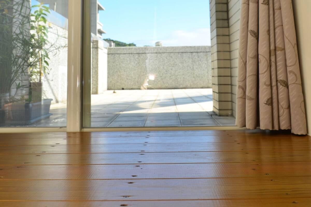 An open sliding glass door leading to a balcony with a clear sky view.