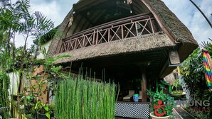 A traditional thatched-roof building with a balcony and a checkered floor. - Capung Sakti Villas – By Fair Future Foundation (Ubud)