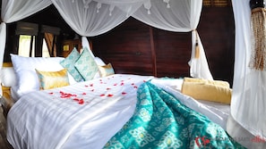 Una cama con dosel, almohadas y manta.