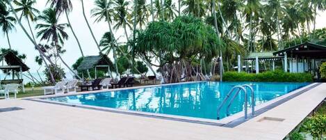 Una piscina al aire libre, sillones reclinables de piscina