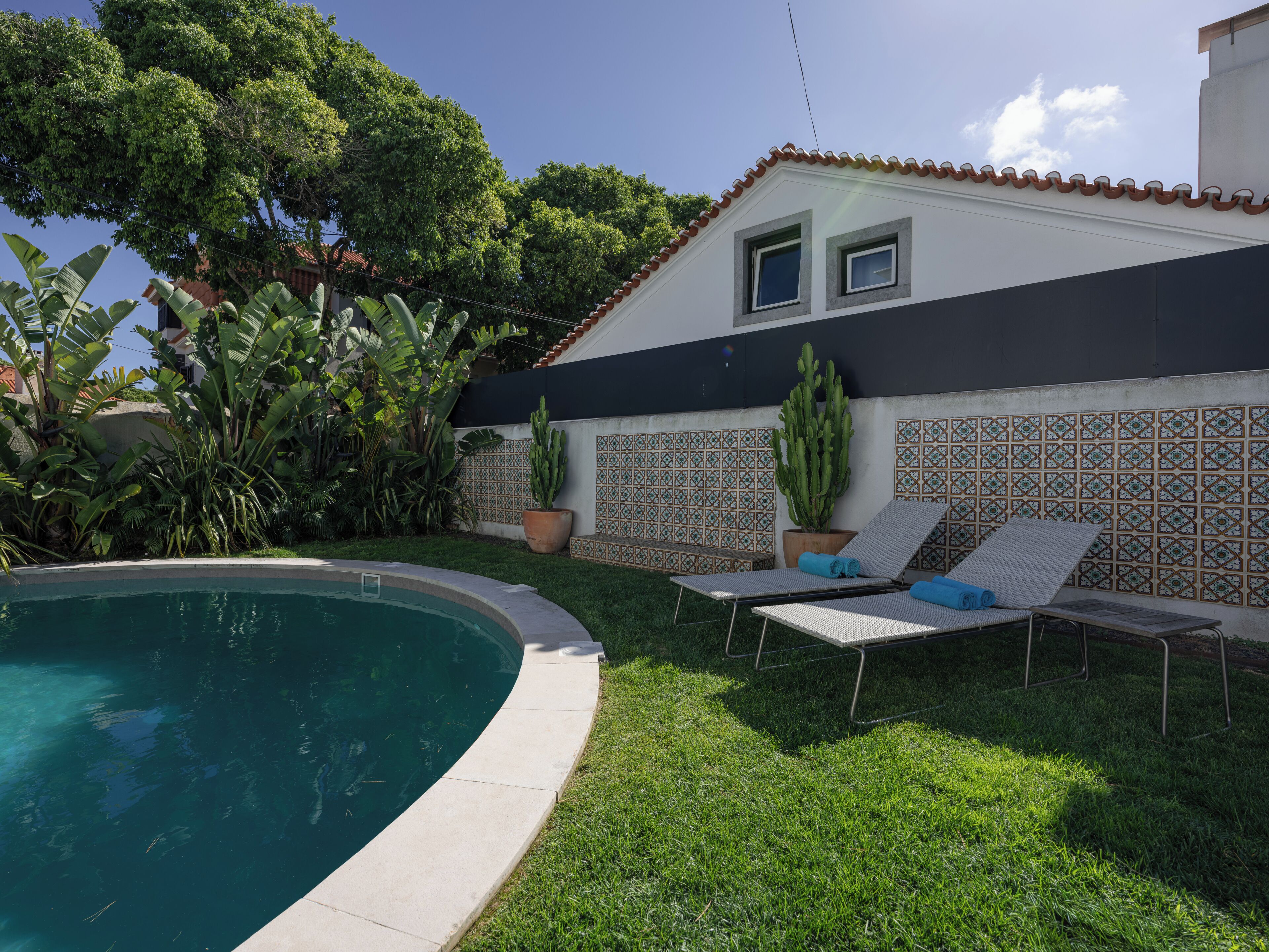 Uma área de piscina com cadeiras de descanso e plantas em vasos.