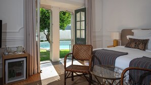 Habitación de hotel con cama, una silla, una mesa, televisión y vista a una piscina.
