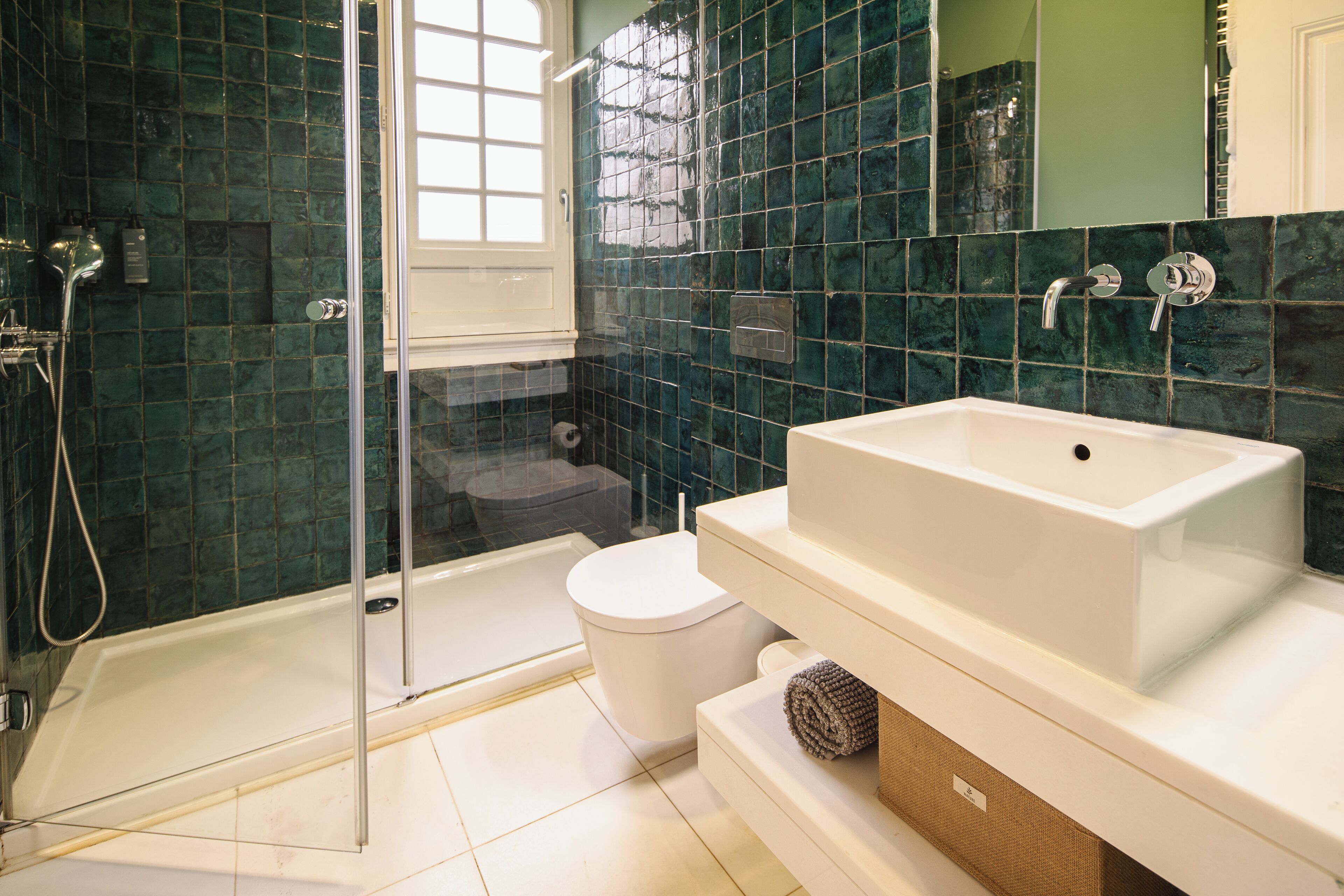 Un baño con cabina de ducha de vidrio, una bañera blanca, un inodoro blanco y un lavamanos grande de color blanco.