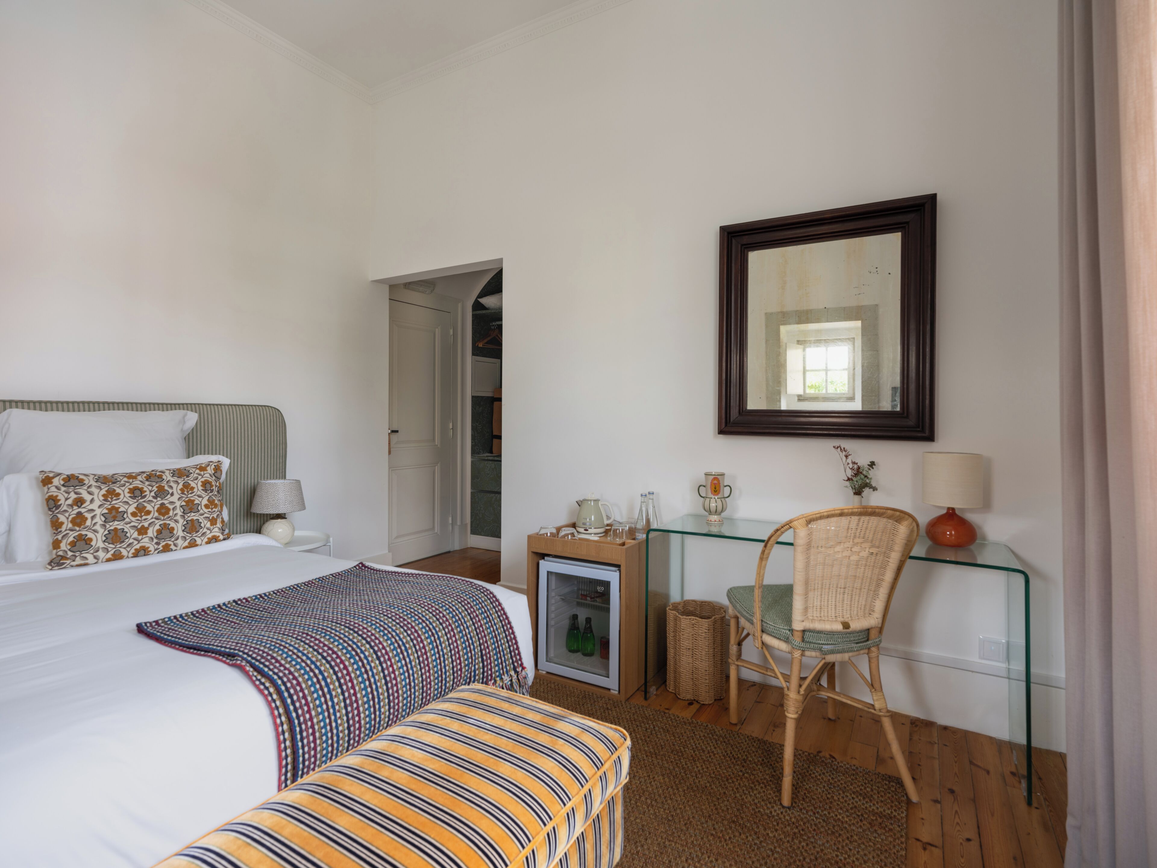 A bedroom with a bed, a desk, a chair, a mirror, and a wardrobe.