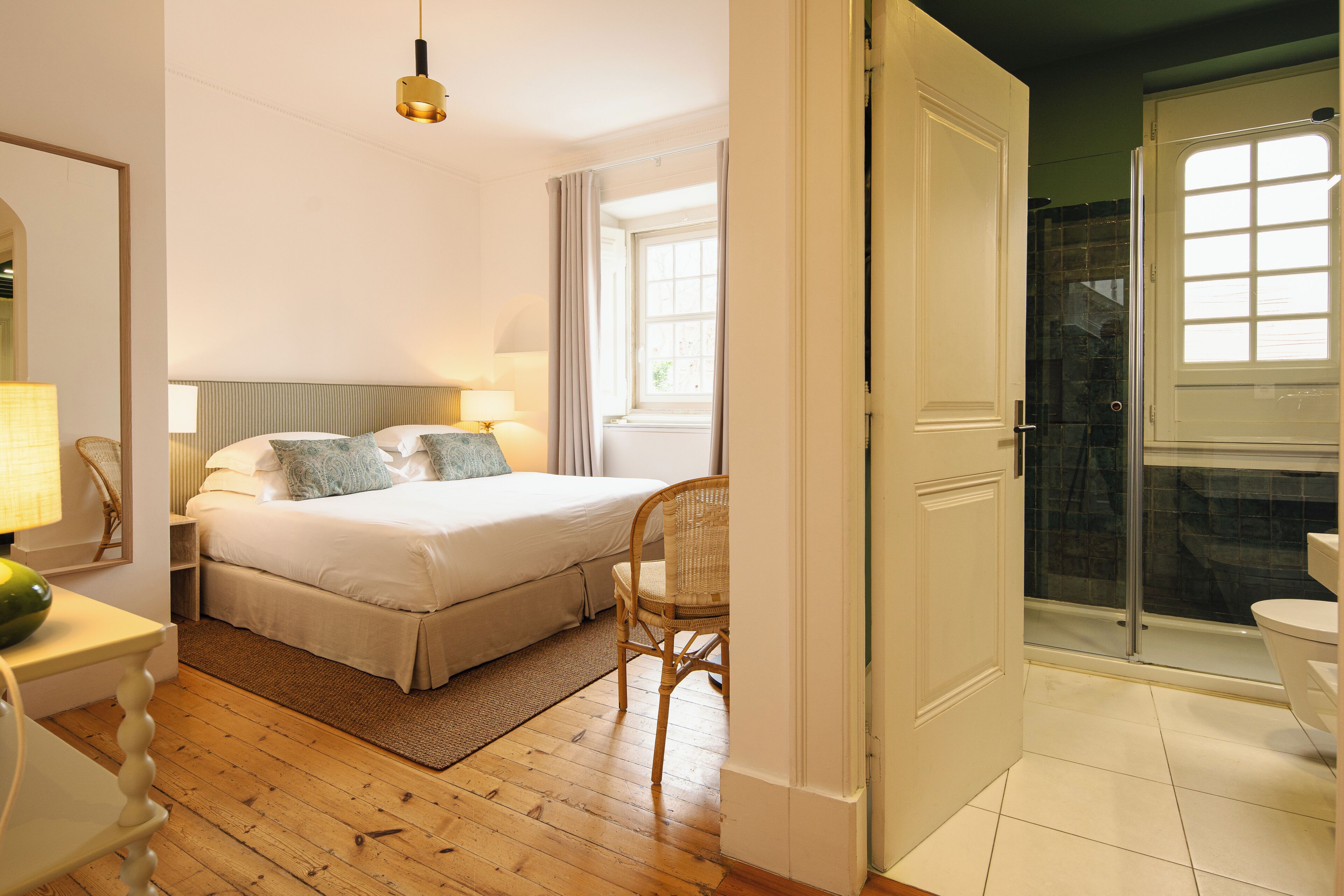 A bedroom with a bed, bedside table, chair, and a window.