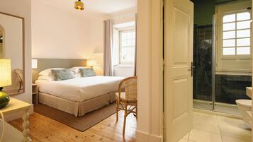 A bedroom with a bed, bedside table, chair, and a window.