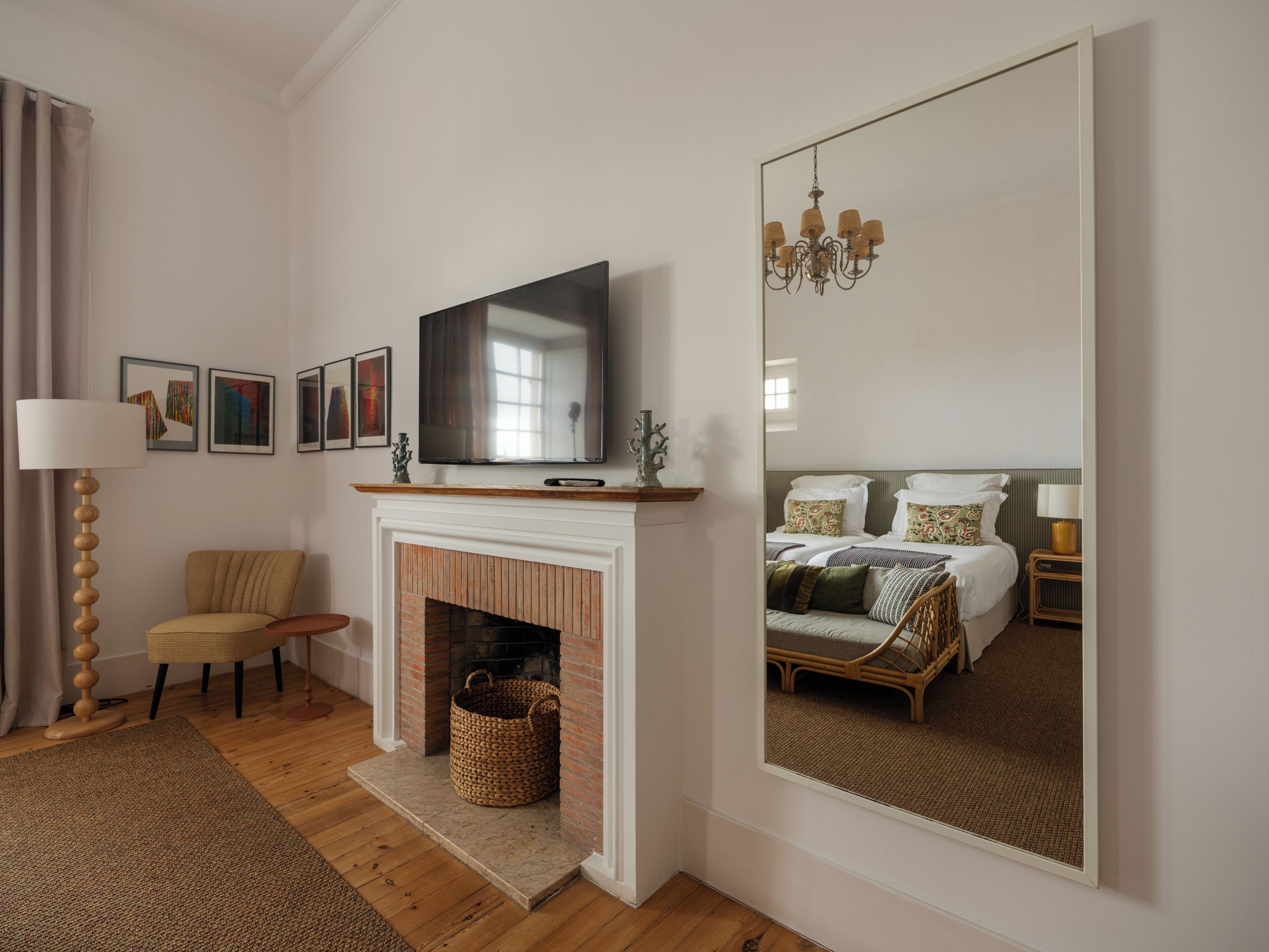 Ein Zimmer mit Kamin, Fernseher, Bett, Sessel und einem großen Spiegel.