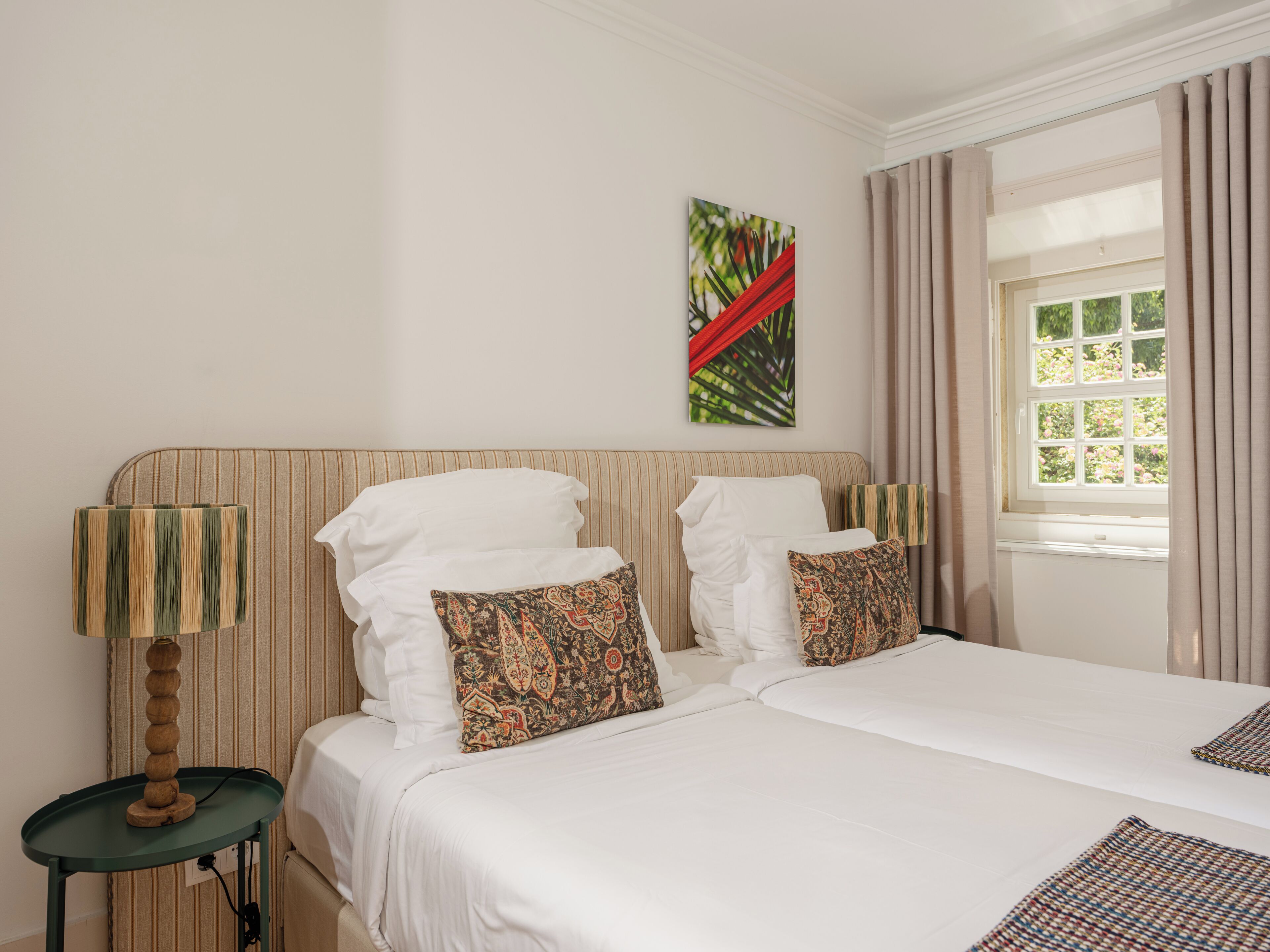 A double bed with white linens, a striped headboard, and two patterned pillows.