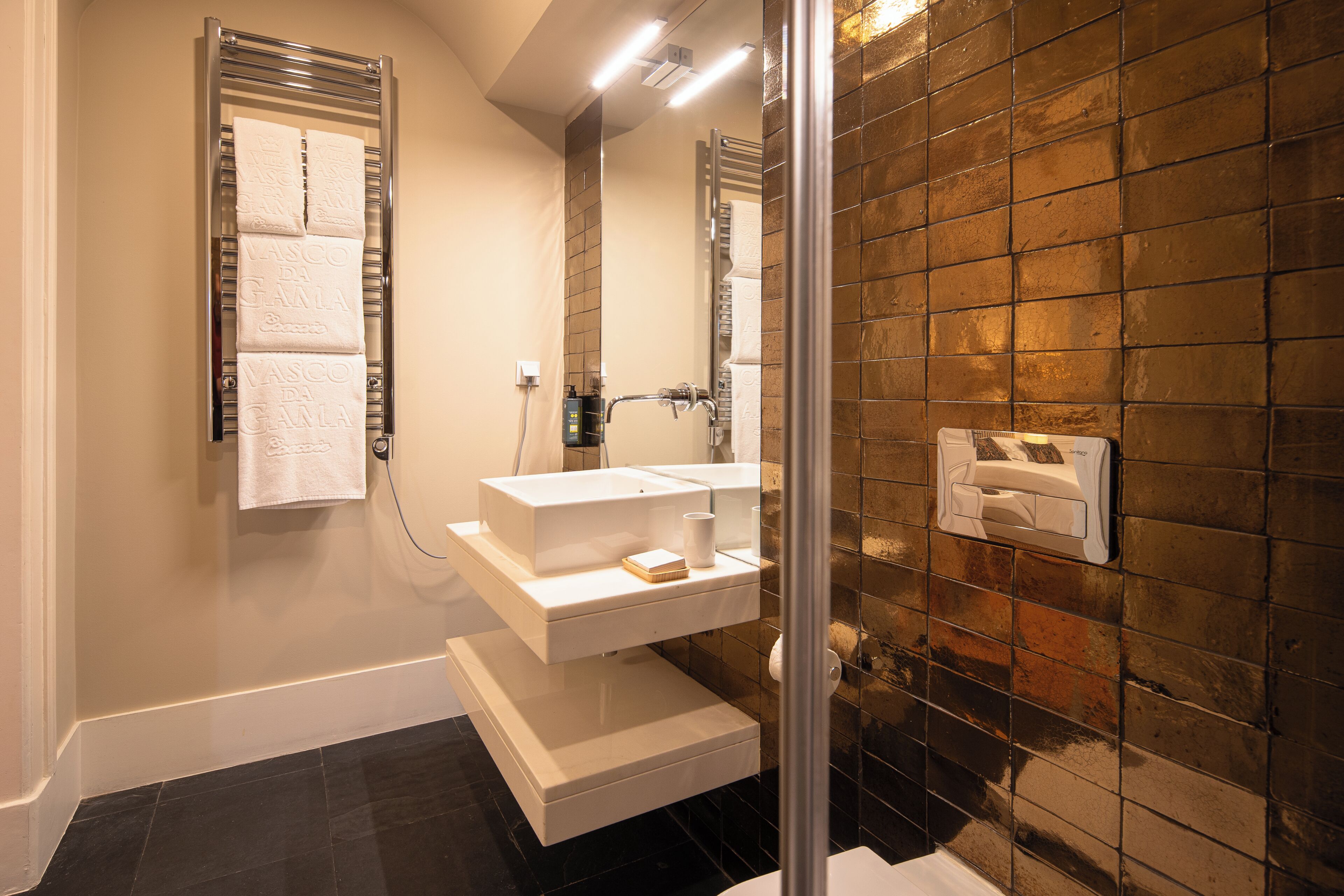 A bathroom with a towel rack, a sink, a mirror, and a shower area.