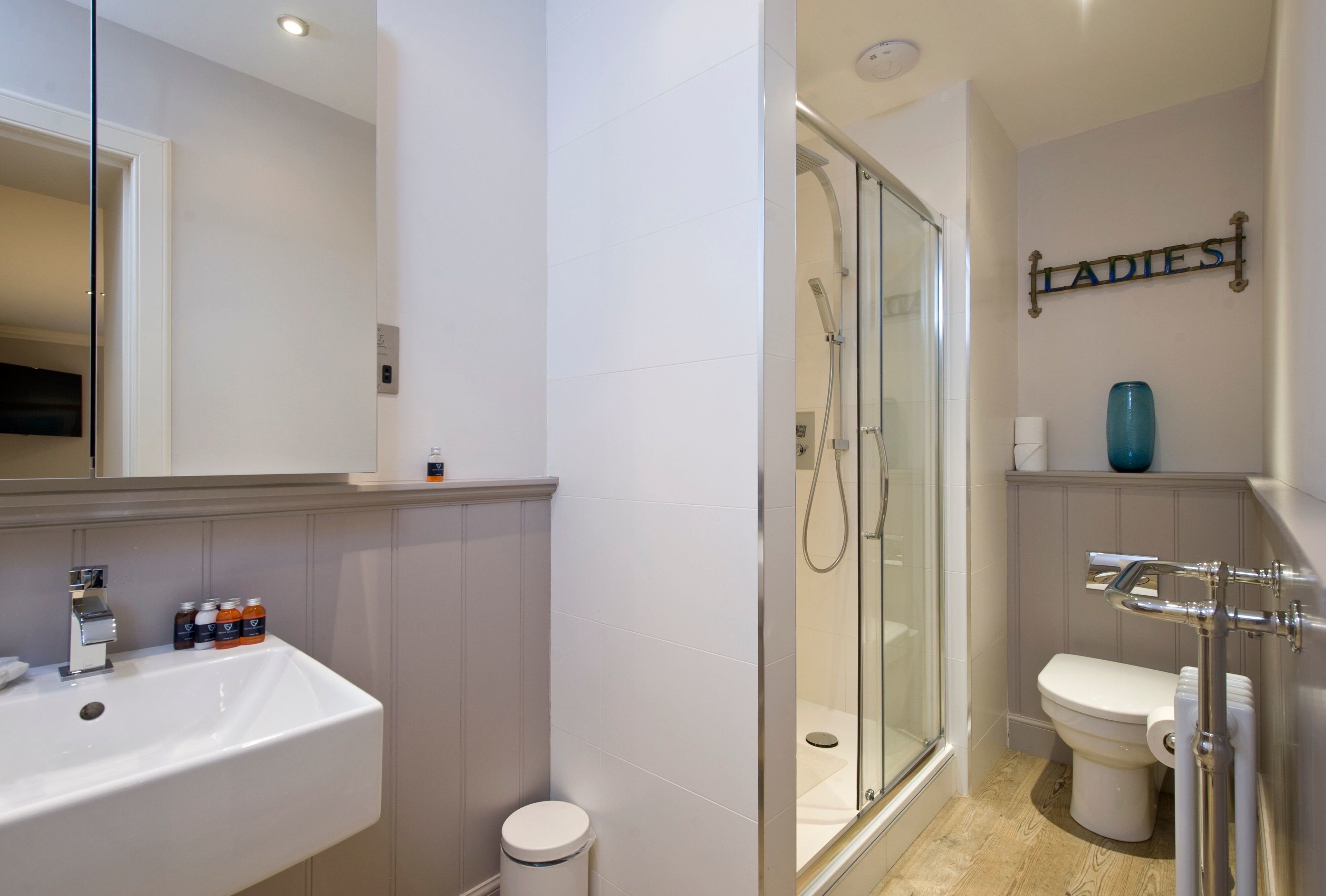 A modern bathroom with a glass-enclosed shower, a white sink, and a toilet.