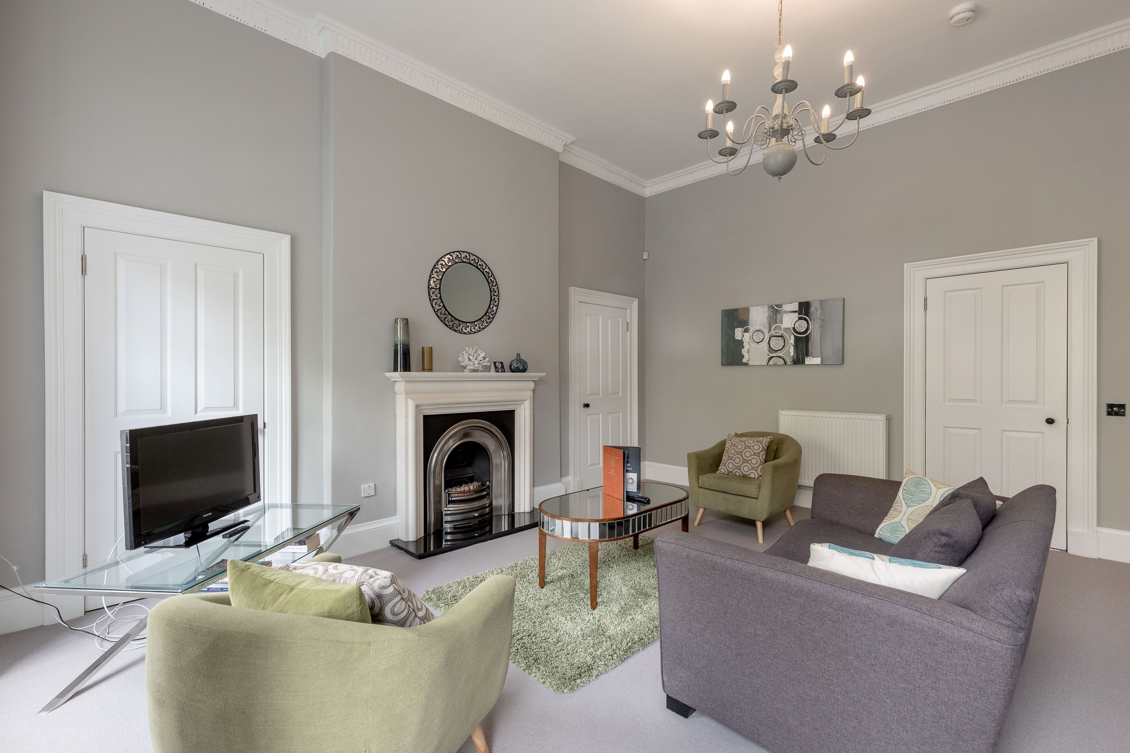 A living room with a fireplace, a television on a glass table, and two sofas.
