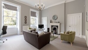 A spacious living room with a fireplace, a television, and a comfortable seating area. - Destiny Scotland - Q-Residence (Edinburgh)