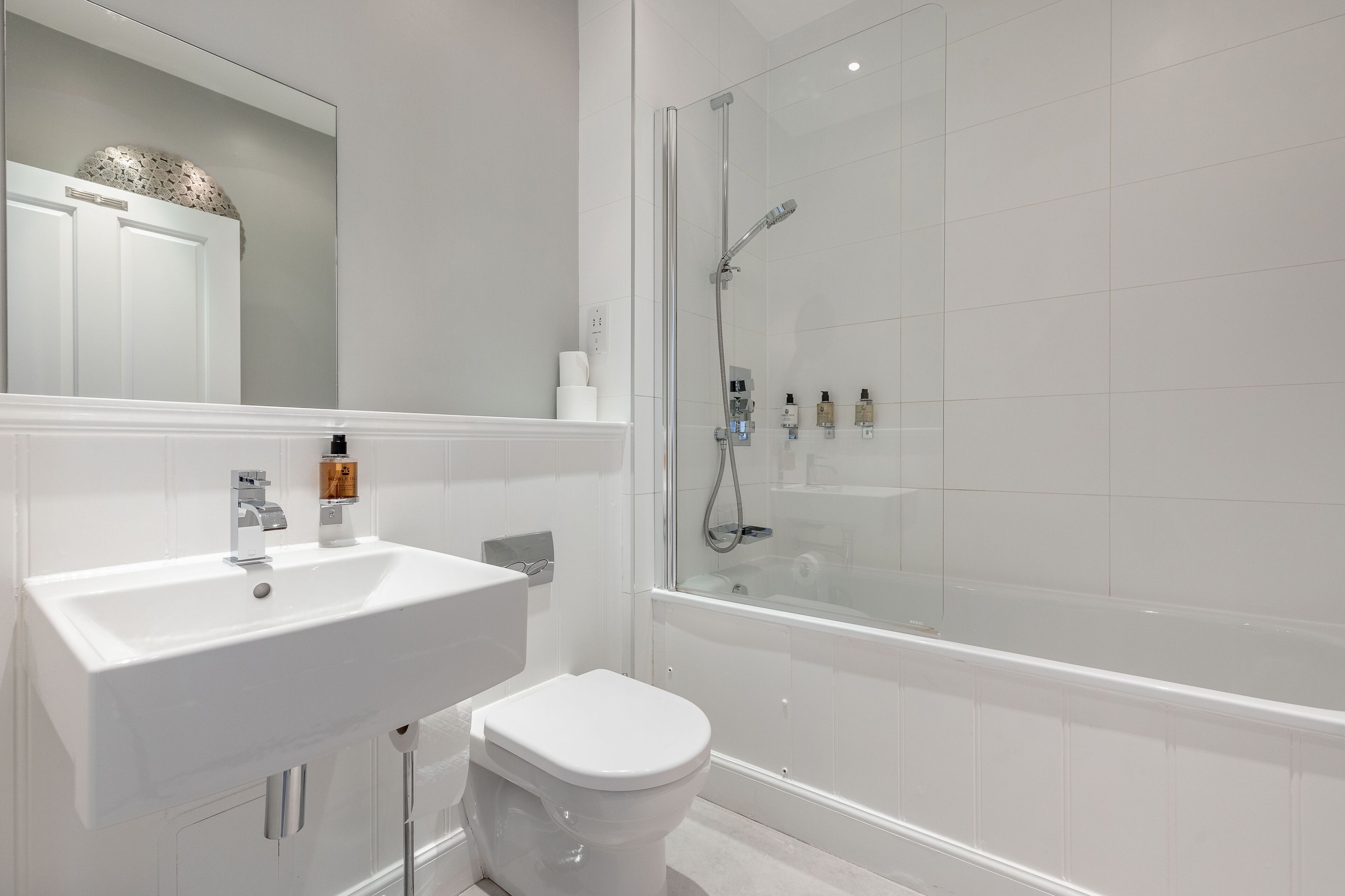 A modern bathroom with a white sink, toilet, and glass-enclosed shower.