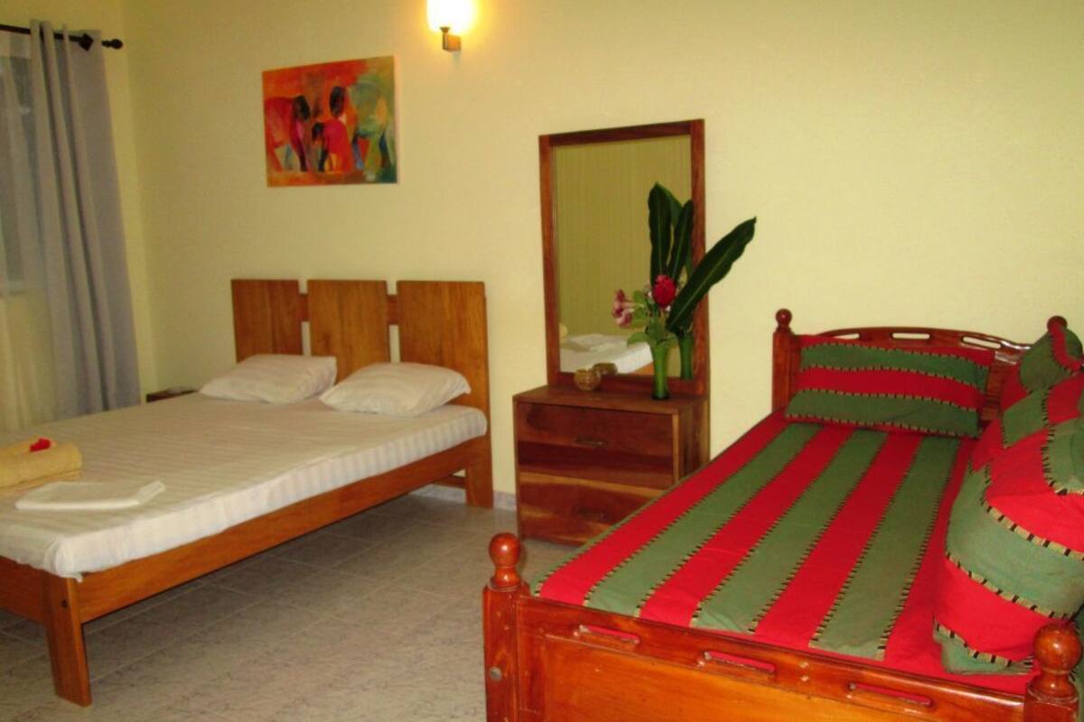 Un dormitorio con dos camas, cabecero de madera, mesita de noche, espejo y un cuadro en la pared.