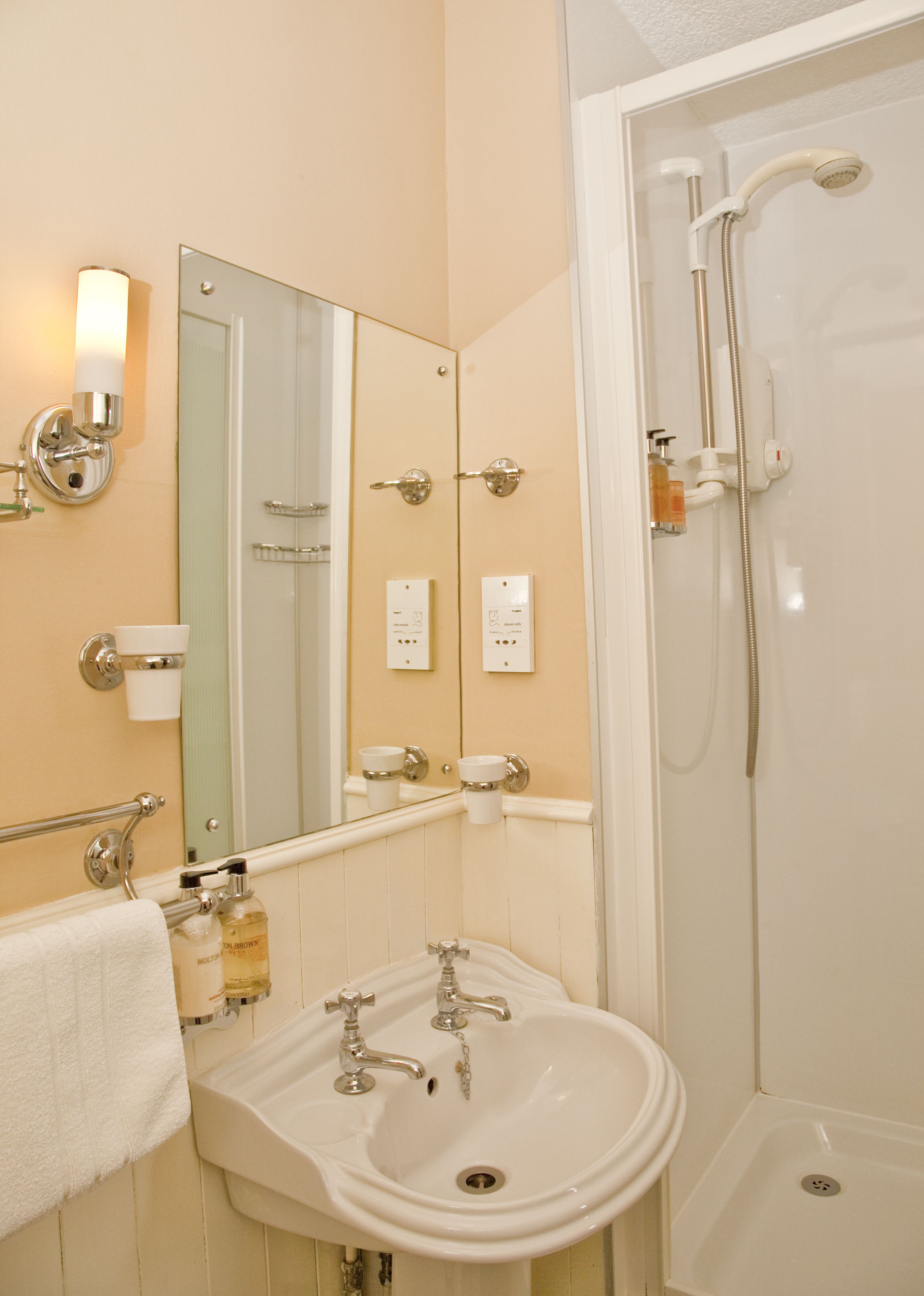 A bathroom with a sink, mirror, towel rack, and a shower.