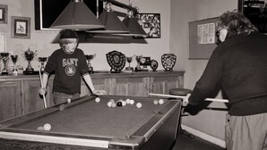 Une table de billard avec des billes, un trophée et un tableau encadré accroché au mur.