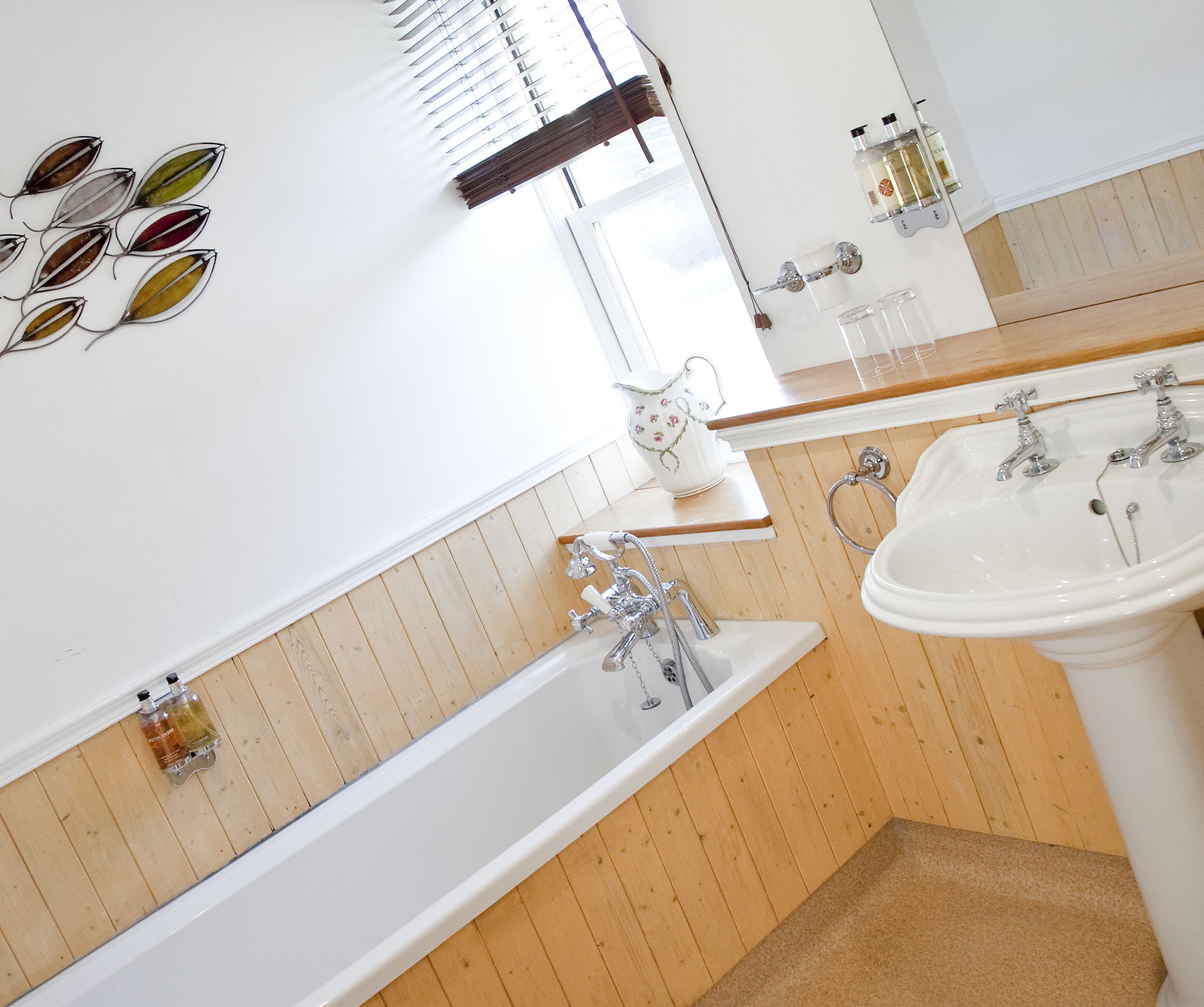 Une salle de bain avec un mur recouvert de panneaux en bois, une baignoire blanche, un lavabo et un miroir.