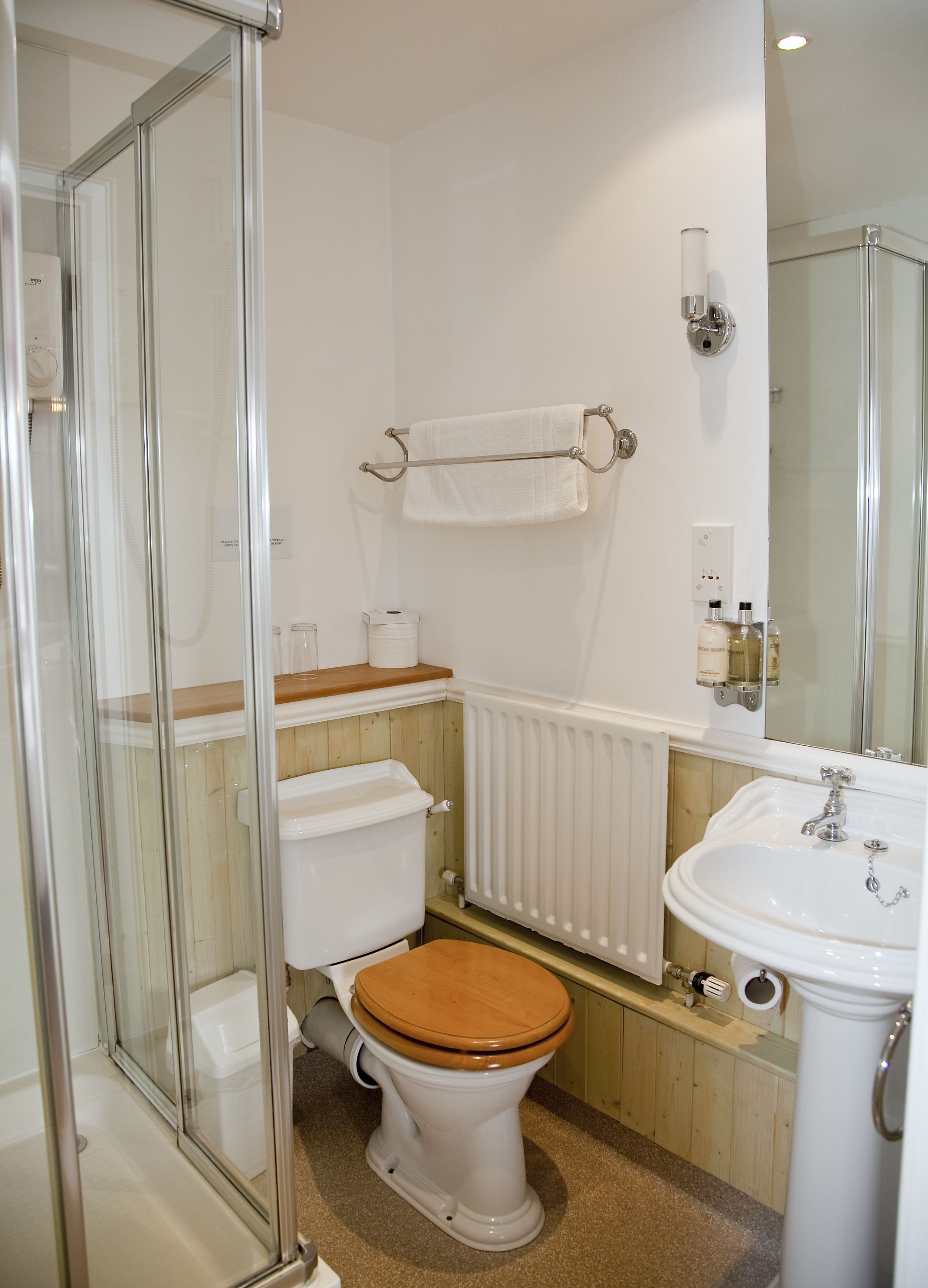 Ein Badezimmer mit Toilette, Waschbecken, einer Duschkabine aus Glas und einem Handtuchhalter.