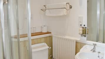 A bathroom with a toilet, a sink, a glass shower enclosure, and a towel rack.