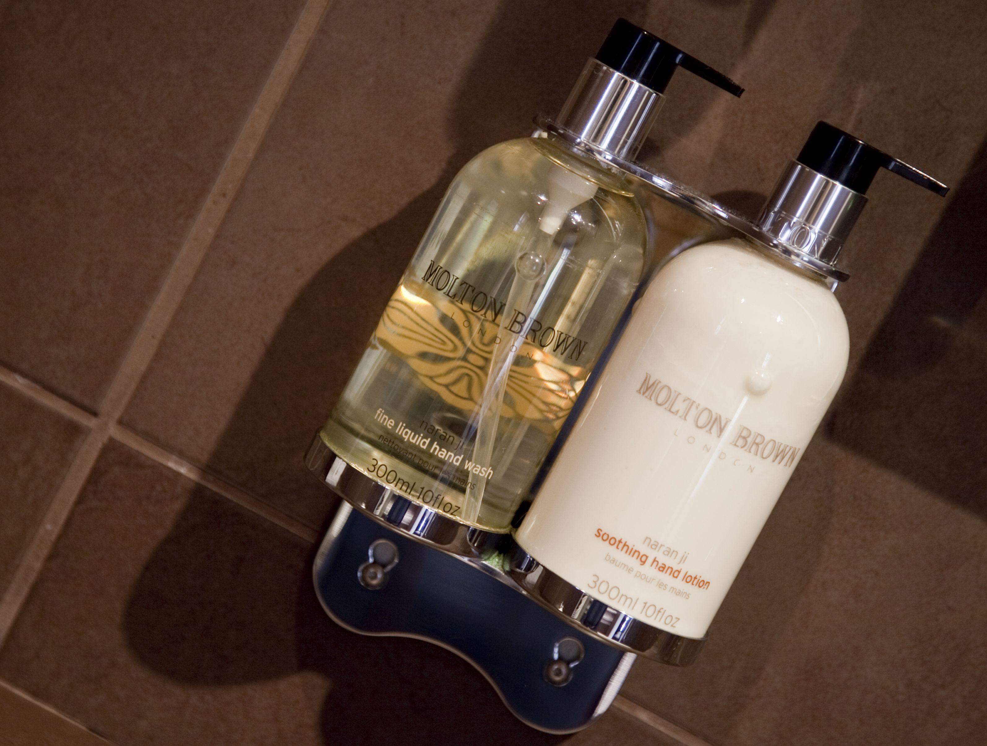 Two bottles of Molton Brown hand wash on a tiled surface.