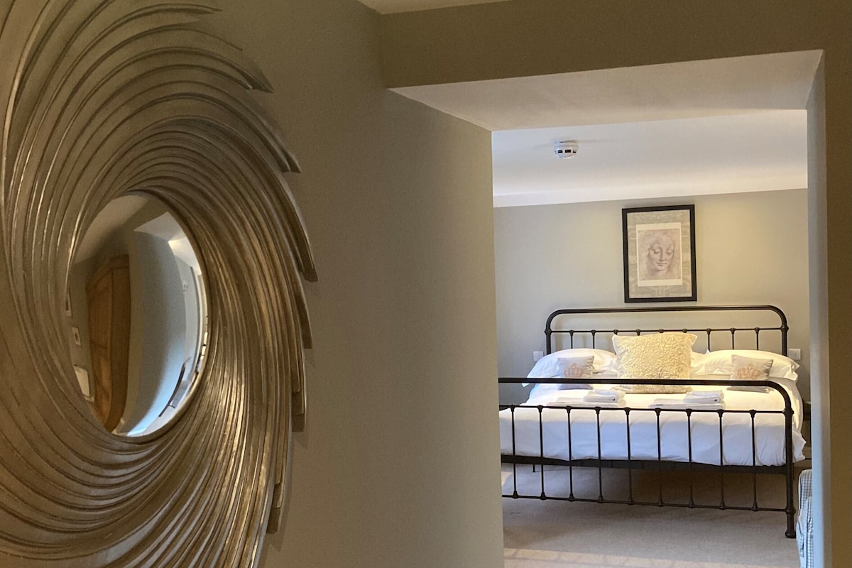 A bedroom with a bed, a circular mirror, and a framed picture on the wall.