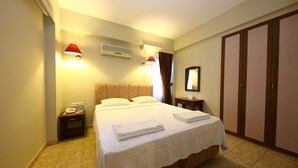 A hotel room with a bed, bedside lamps, a nightstand, a wardrobe, and an air conditioning unit. - Mr. Dim Exclusive Apart Hotel (Fethiye)