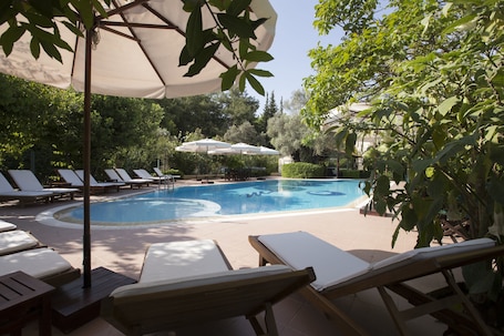 Una piscina al aire libre, sombrillas, sillones reclinables de piscina
