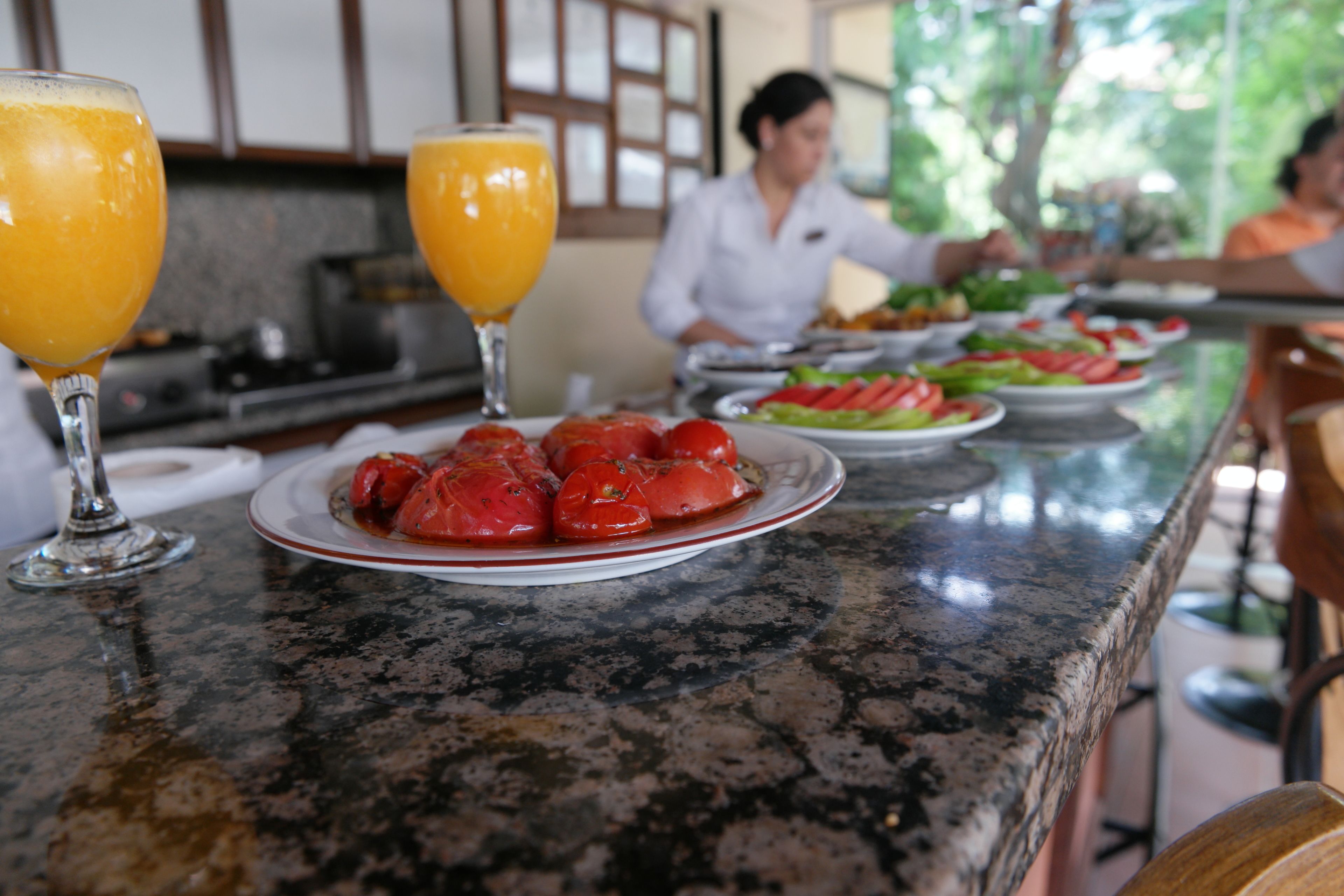 A kitchen counter with a plate of tomatoes and two glasses of orange juice.